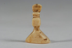 A miniature ancient Inuit game piece carved from walrus ivory